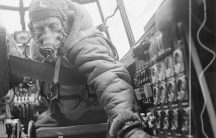 Flying Officer checks settings on control panel on an Avro Lancaster B Mark III